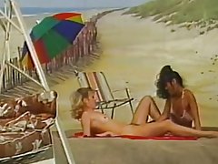 Dhá lesbians ag imirt ar an trá cúlra